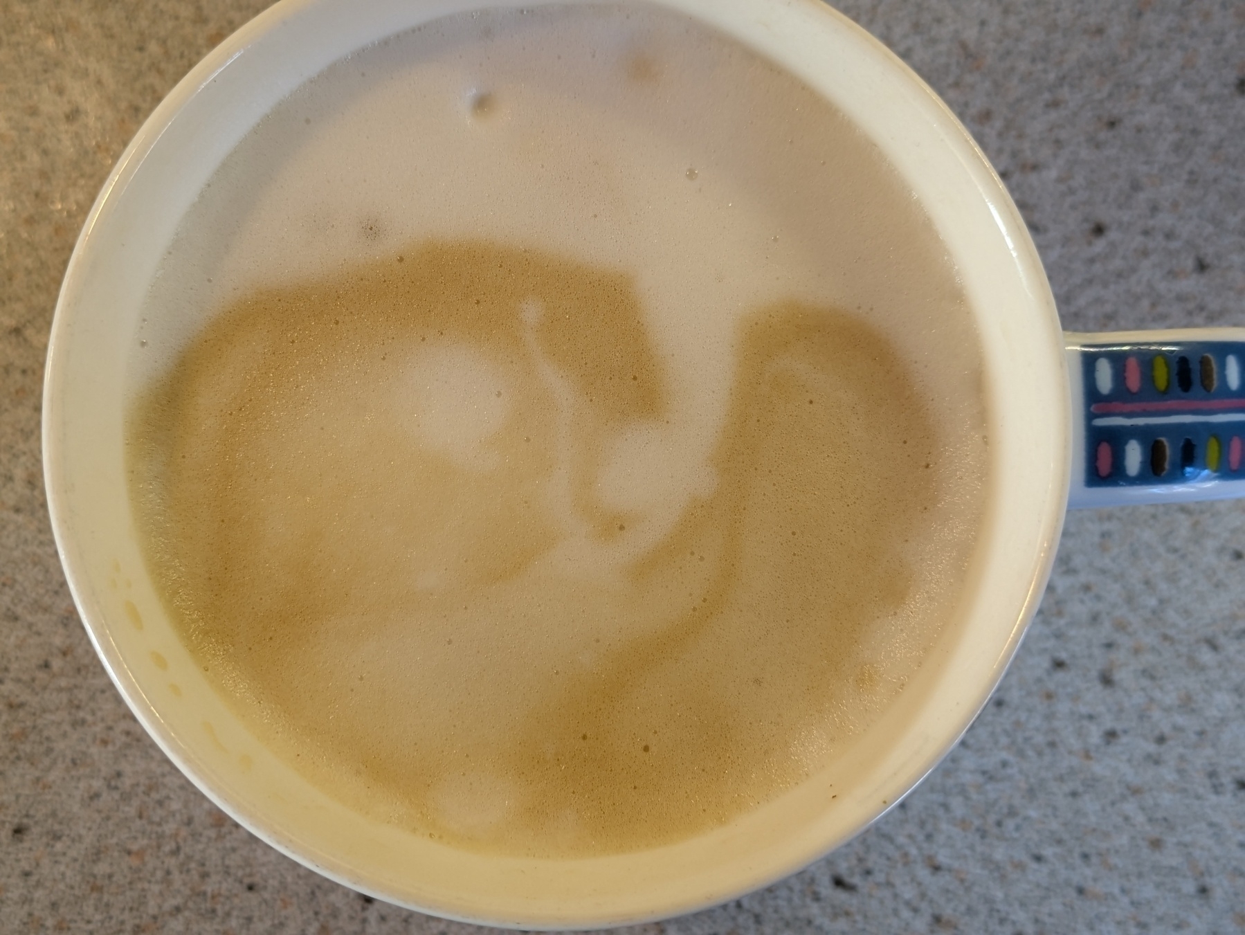 A cup of coffee with frothy milk on top creating a swirl pattern.